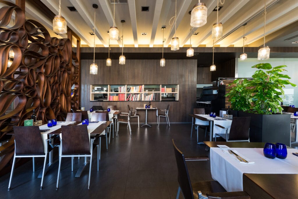 Vista del elegante salón principal de Peix & Brases con mesas preparadas, techos de madera y luz cálida.